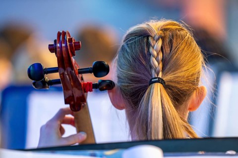 Young girl plays a cello at a concert