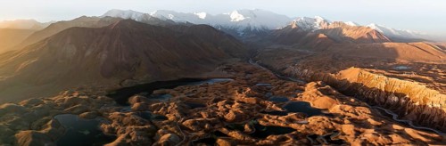 PanoramaWhite glaciated and snow-covered mountain peak Pik Lenin at sunrise, hilly landscape with