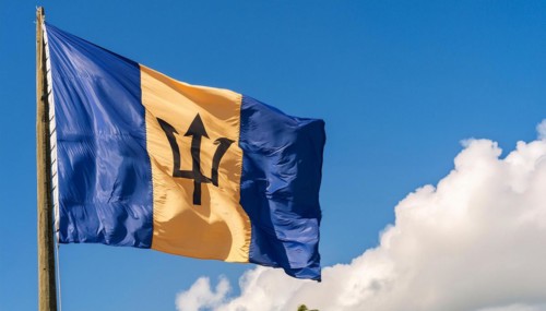 The Barbados flag flutters in the wind, isolated against a blue sky