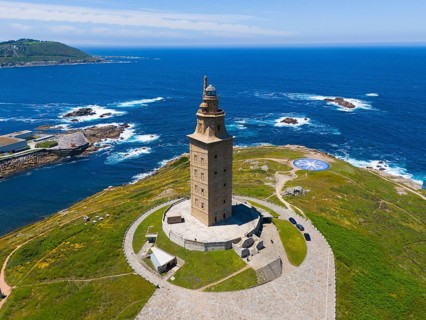 Ancient lighthouse on a land mass surrounded by crystal blue ocean and green vegetation under a
