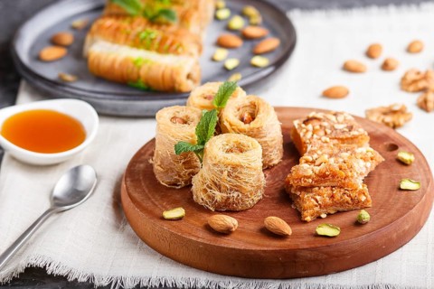 Set of various traditional arabic sweets: baklava, kunafa, basbus in ceramic plates on a gray