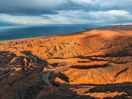 Riverbed runs through a landscape of eroded hills, badlands at sunset, Issyk Kul Lake in the