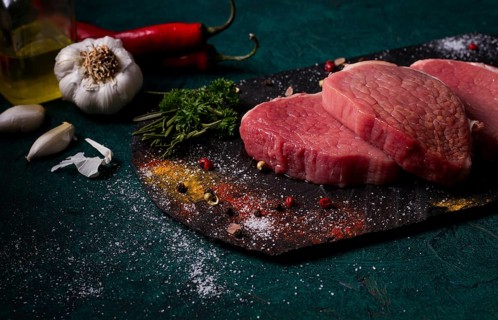 Fresh raw beef meat, Medallions, on black slate, with spices, close-up, horizontal