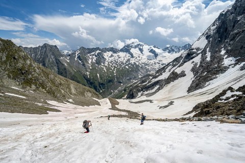 Mountaineers hiking in a snowfield, Nördliche Mörchnerscharte, behind mountain peak Kleiner