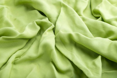 Fragment of green linen tissue. Side view, natural textile background and texture. wave concept,