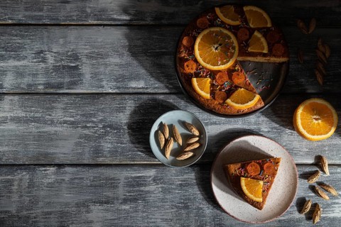 Orange cake on a gray wooden background. Hard light. contrast, low key. Top view, flat lay, copy