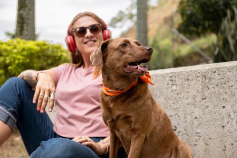 Pretty woman sitting on a concrete staircase, listening to music, accompanied by her dog. Selective