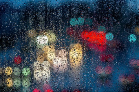 Rainy weather, road traffic, raindrops on a window pane, behind, blurred, lights of vehicles on a