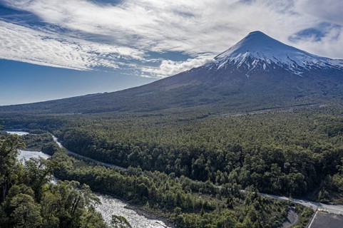 Snow-capped volcano Osorno rising high above river Rio Petrohue, early spring, chilenean lake