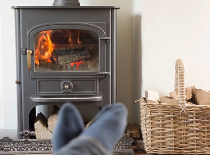Roaring domestic household wood burning ClearView stove fire log basket with feet up in foreground