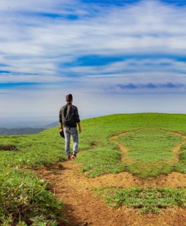 View of backpacker man walking on the beautiful hill. Backpacker walking on a beautiful hill