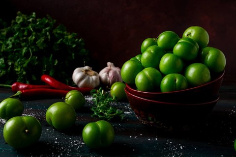 Tkemali, green cherry plum, with ingredients for sauce, cilantro, mint, hot pepper, garlic, on a