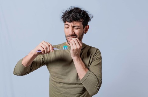 Person with gingivitis holding toothbrush. People holding toothbrush with gum pain. Man holding