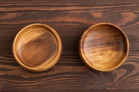 Two empty brown wooden bowl on brown wooden background. Top view, copy space, flat lay
