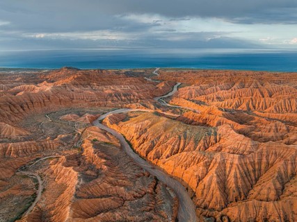 Riverbed runs through a landscape of eroded hills, badlands at sunset, Issyk Kul Lake in the