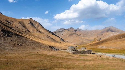 Historic caravanserai Tash Rabat from the 15th century, in the evening light with golden hills,