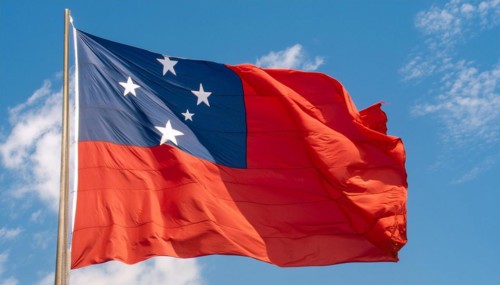 The flag of Samoa, fluttering in the wind, isolated against a blue sky