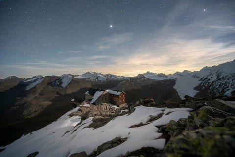 Mountain landscape under a starry sky, night shot, mountain hut Ramolhaus in autumn with snow, view