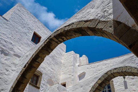View upwards of arches and white walls against a blue sky, part of a historic monastery, Inside the