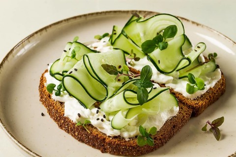 Breakfast, cereal bread sandwiches, cream cheese, sliced cucumber, with micro greenery on a light