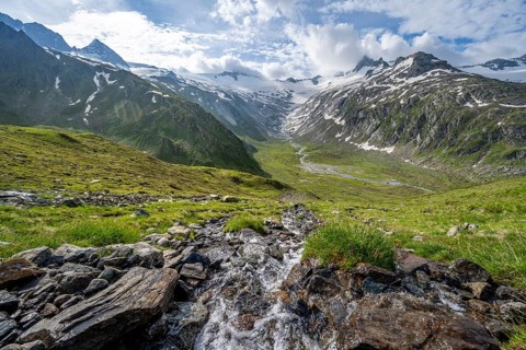 Picturesque mountain landscape with mountain stream, mountain summit with snow and glacier