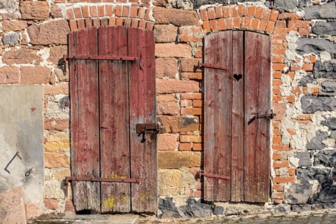 Weathered wooden doors to stable and loo, with heart, façade made of sandstone, natural stone,