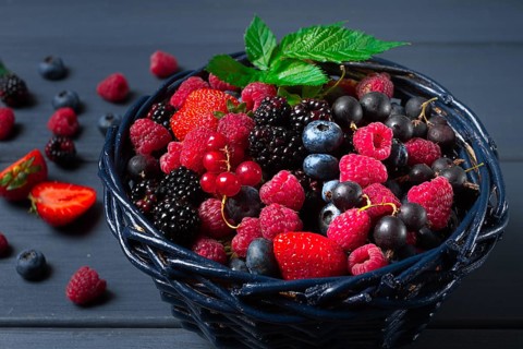 Mix of fresh berries, in a basket, on a wooden gray table, no people, top view