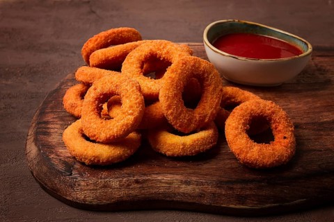 Crispy chicken rings, fried, on a wooden board, close-up