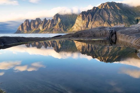 Reflections of clouds, rocks and the Devil's Tooth mountain in the evening sunlight, Tungeneset,