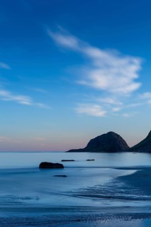 Seascape on the beach at Haukland. The sky is blue. At night at the time of the midnight sun in