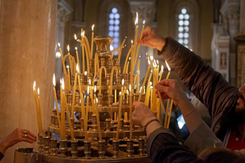 Several hands put burning candles into a candlestick, Greek Orthodox Cathedral of the Annunciation,