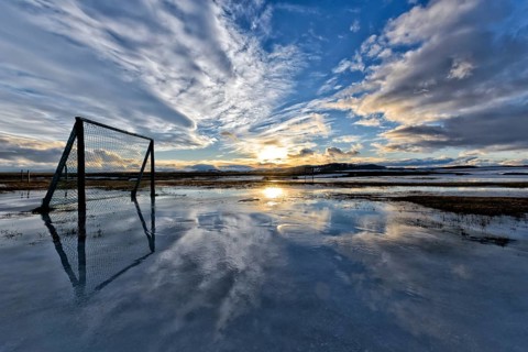 Sunset over clouds, football playground flooded with melting snow, winter, farm Mödrudalur located
