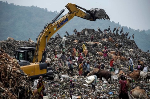 Municipality workers working with excavator as rag pickers searches for recyclable materials next