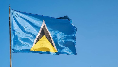 The flag of St Lucia, Caribbean, flutters in the wind, isolated against a blue sky