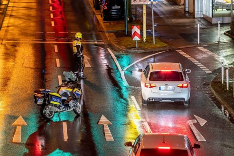 Policeman with motorbike, in rainy weather, blocking a road, police motorbike with blue light