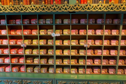 A shelf in the shop stocked with many tins of sardines in different colours and designs, giving a