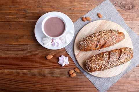 Rye bread with sunflower seeds, sesame and flax with cup of cocoa on brown wooden background. top