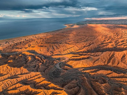 Landscape of eroded hills, badlands at sunset, Issyk Kul Lake in the background, aerial view,