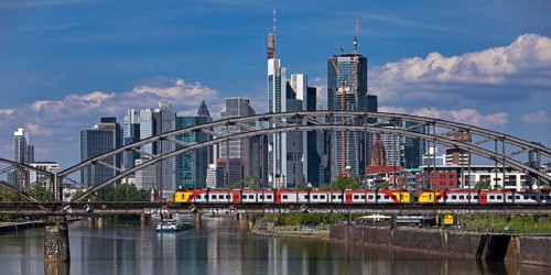 Main with regional railway on the Deutschherrnbrücke and a cargo ship in front of the skyline of