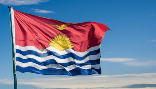 The flag of Kiribati, Polynesia, flutters in the wind, isolated against a blue sky