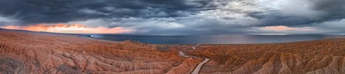 Panorama, landscape of eroded hills, badlands at sunset, Issyk Kul Lake in the background, aerial