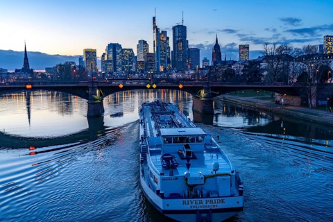 Skyline of the city centre of Frankfurt am Main, river Main, dusk, Ignatz-Bubis-Bridge, cargo ship,