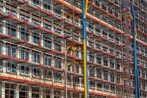 Large construction site, scaffolded shell of an office building complex, air hoses for building