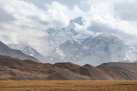 Glaciated, cloud-covered mountain peaks and golden meadows, Lenin Peak, Trans Alay Mountains, Pamir