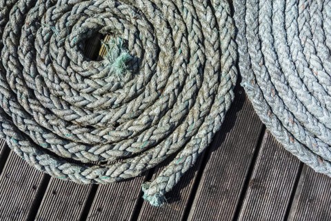 Close up of two coiled braided ropes, plaited hawsers on deck