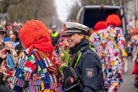 Rose Monday parade in Düsseldorf, policemen on duty at the street carnival, with flower