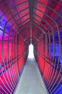A long tunnel with red lighting and metallic structures conveys a futuristic and industrial