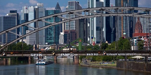 The river Main with the Deutschherrnbrücke bridge and a barge in front of the skyline of Frankfurt