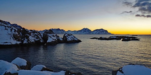 Impressive winter landscape with snow-covered mountains and rocks in a calm sea at sunset, Winter,
