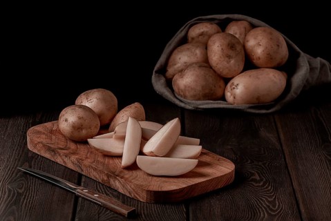 Raw potatoes, sliced, on a wooden table, top view, no people